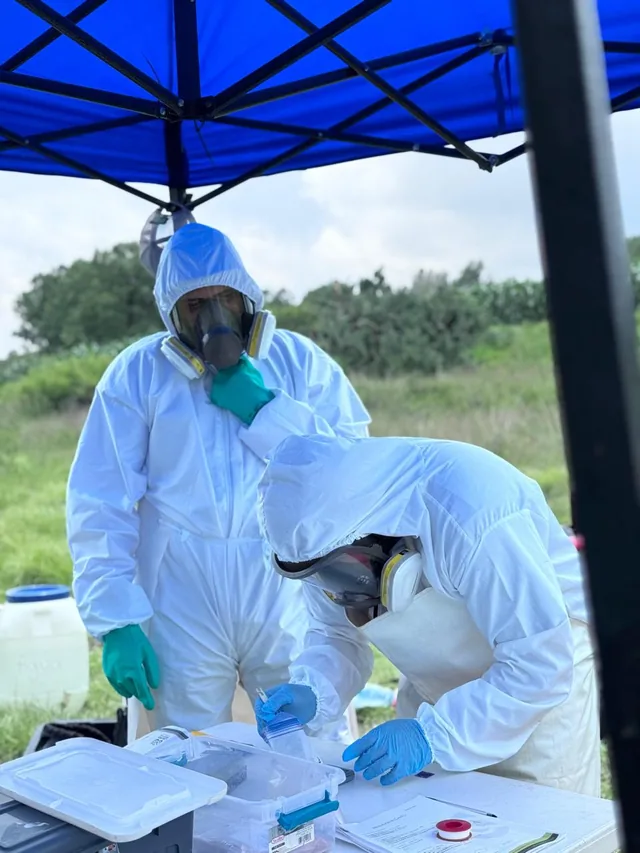 Personal técnico con equipo de protección durante una actividad de muestreo en campo.